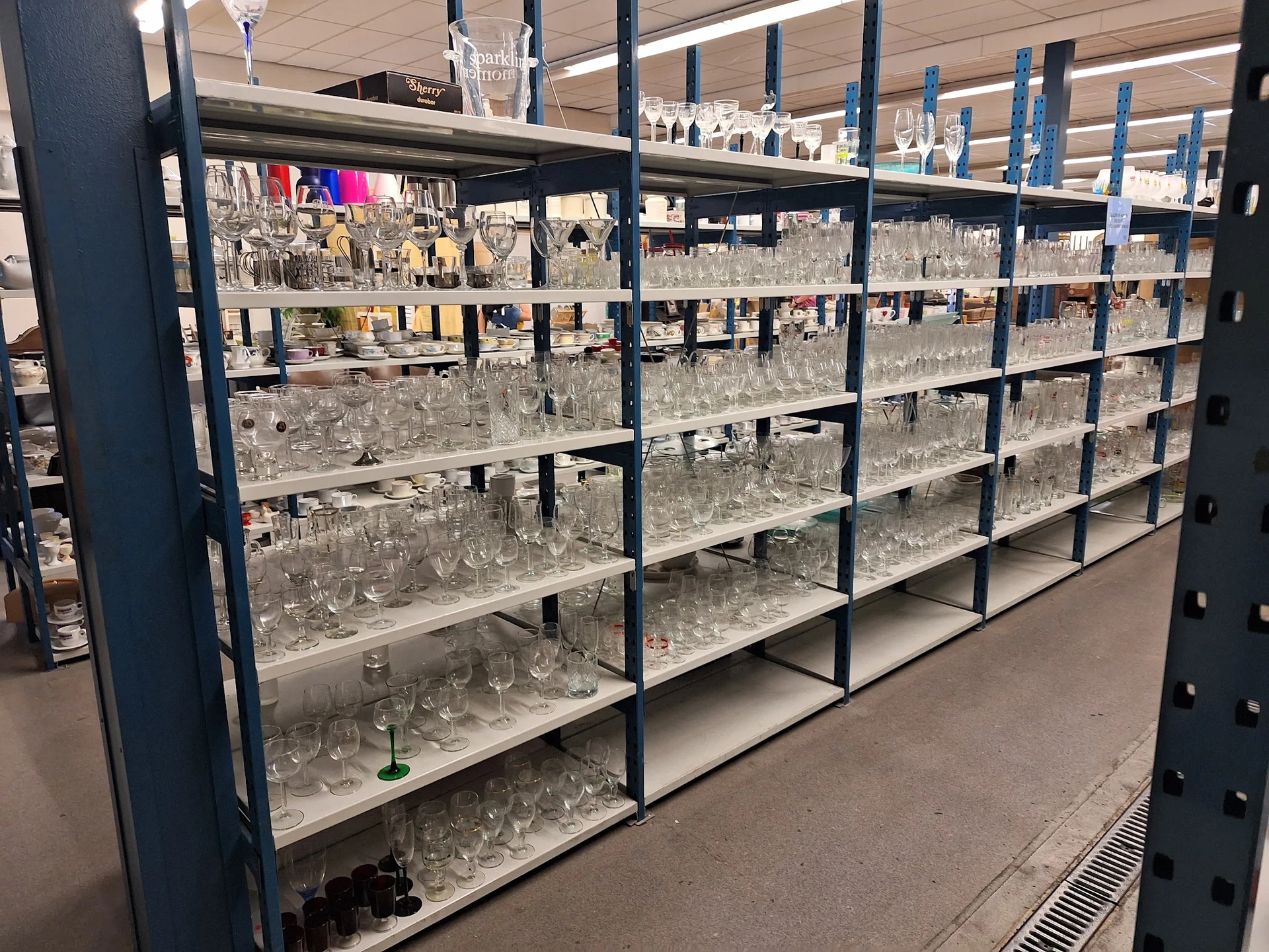 Stellingen vol glazen drinkglazen en kristal in verschillende vormen en maten