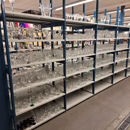 Stellingen vol glazen drinkglazen en kristal in verschillende vormen en maten