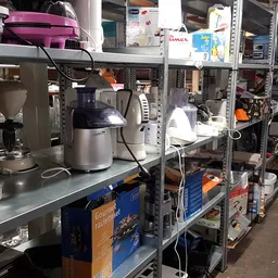Stellingen met huishoudelijke apparaten en keukengerei in een kringloopwinkel