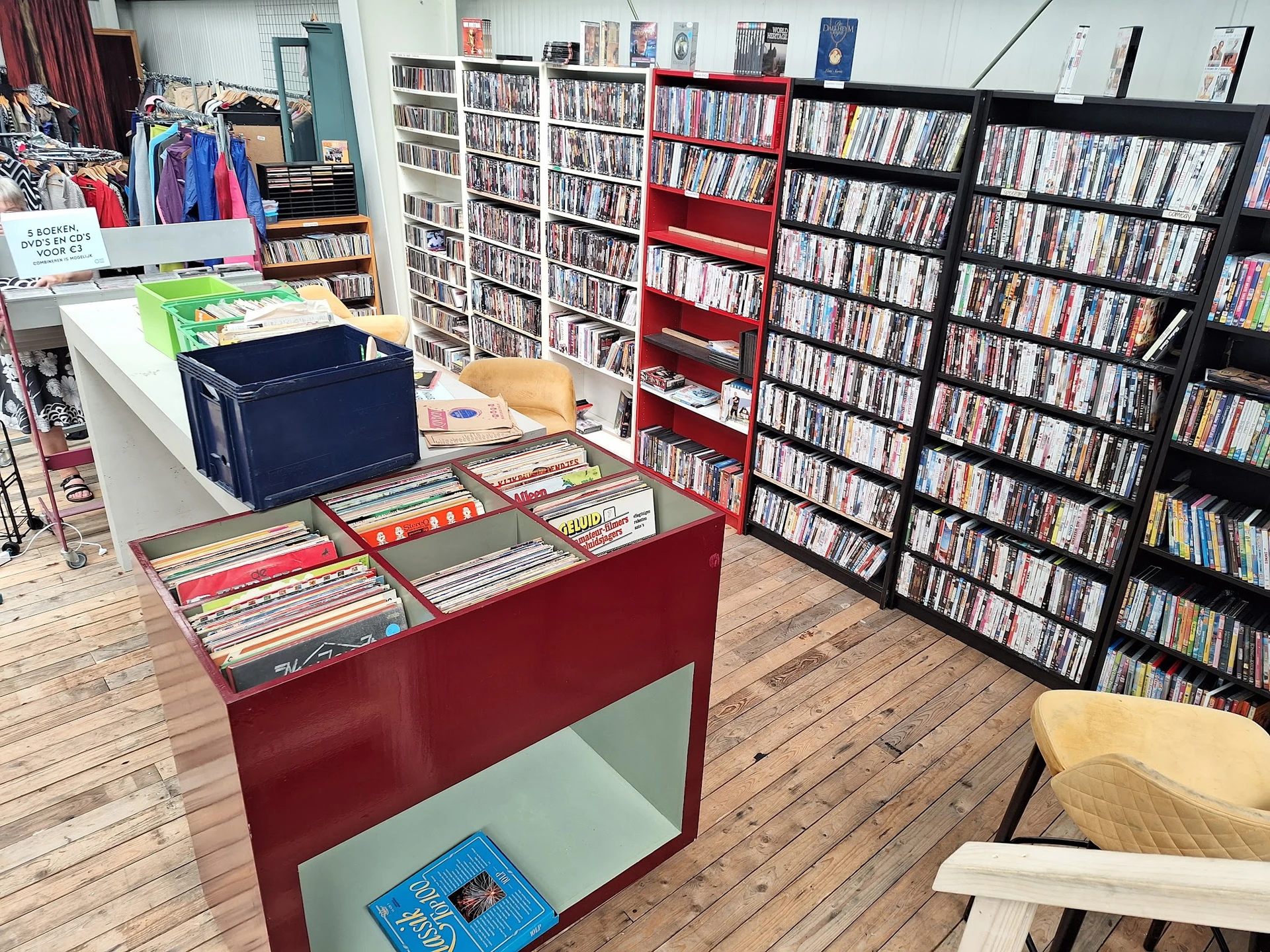 Winkelvloer met media-afdeling: rode en zwarte stellingen met dvd's en cd's, rode toonbank met uitgestalde items