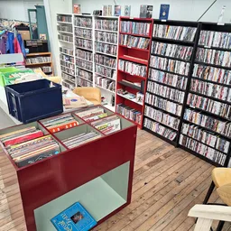 Winkelvloer met media-afdeling: rode en zwarte stellingen met dvd's en cd's, rode toonbank met uitgestalde items