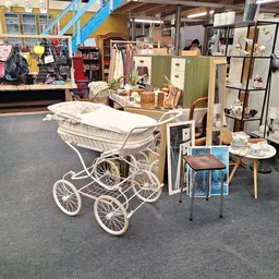 Winkelvloer van kringloopwinkel met vintage kinderwagen, meubels, kleding en huishoudartikelen uitgestald