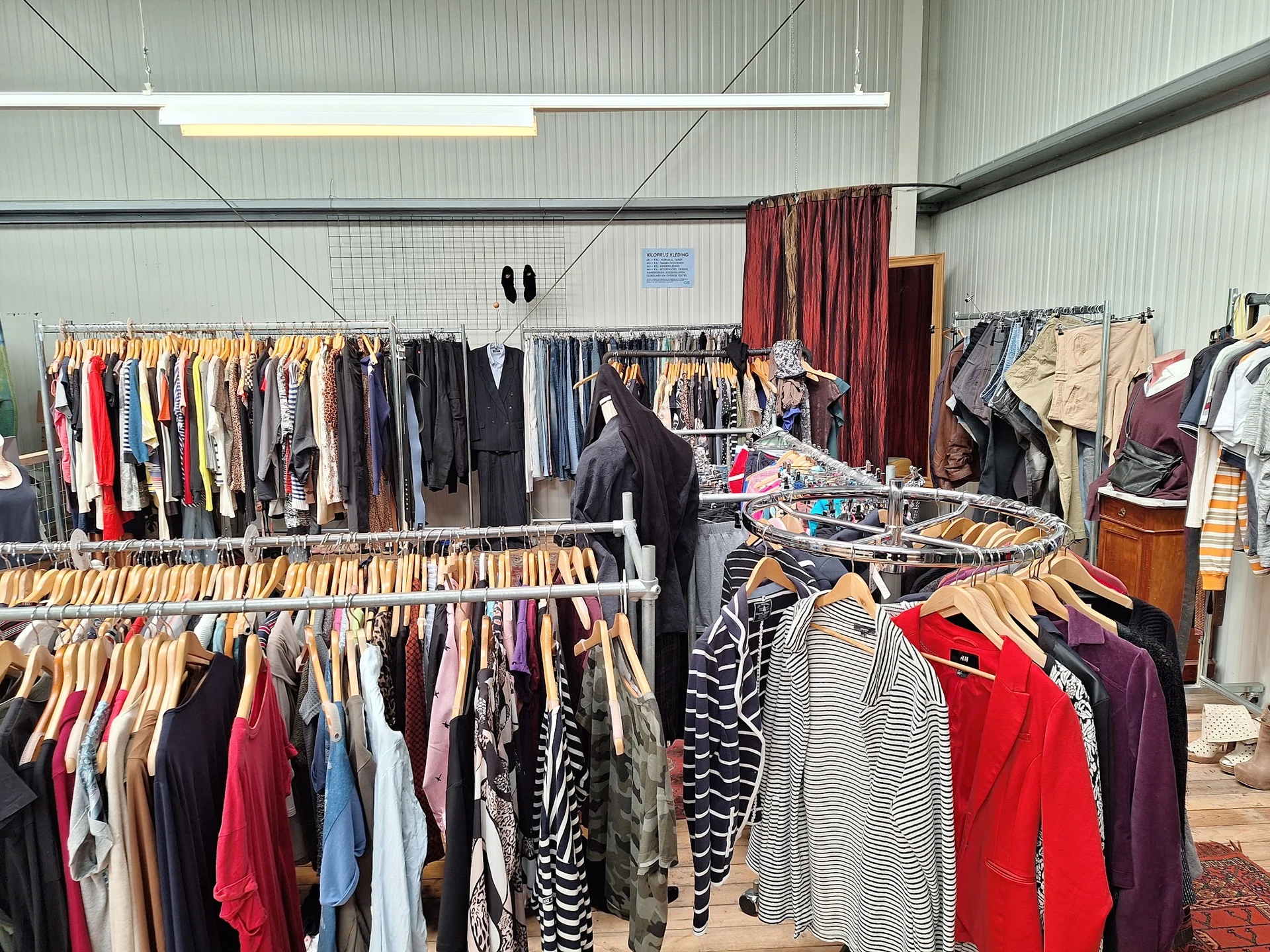 Rekken met tweedehands kleding op hangers in een kringloopwinkel