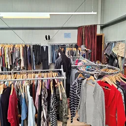 Rekken met tweedehands kleding op hangers in een kringloopwinkel