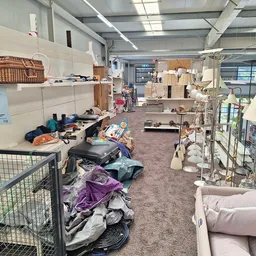 Winkelvloer met diverse tweedehandsartikelen, meubels en spullen verspreid over de grond en in rekken