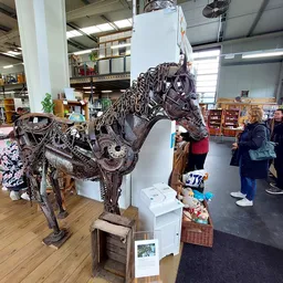 Groot decoratief paardenbeeld van metaal, tentoongesteld in een kringloopwinkel