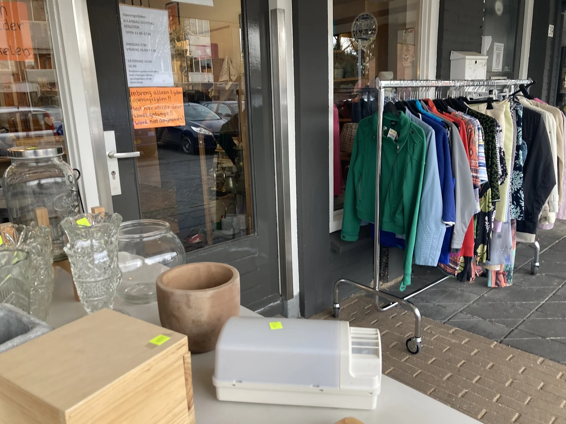 Winkelinterieur met kledingrek, glazen voorwerpen en decoratie op toonbank