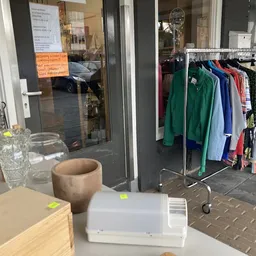 Winkelinterieur met kledingrek, glazen voorwerpen en decoratie op toonbank