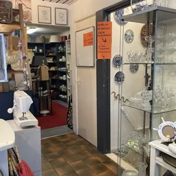 Winkelinterieur met glazen vitrinekast, stellingen, kunstwerk aan muur en diverse spullen