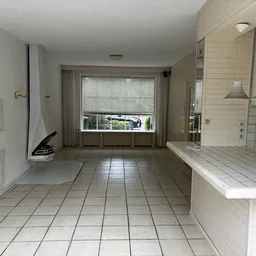 Ruime keuken met tegelvloer, witte tegelmuren, raamwerk en hanglampen, ingericht als showroom