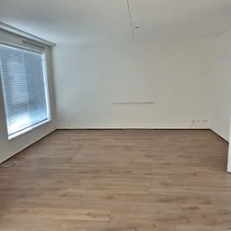Leeg winkelinterieur met houten vloer, wit geschilderde muren en raam met jaloeziën