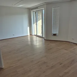 Lege winkelruimte met houten vloer, witte muren en openslaande deuren naar een balkon
