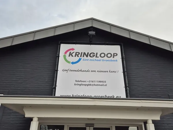 Zwarte houten gevel van kringloopwinkel met wit informatiebord en winkelnaam Kringloop