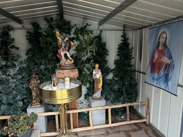 Overdekt interieur met religieuze beelden, planten en decoraties rond een gouden altaar
