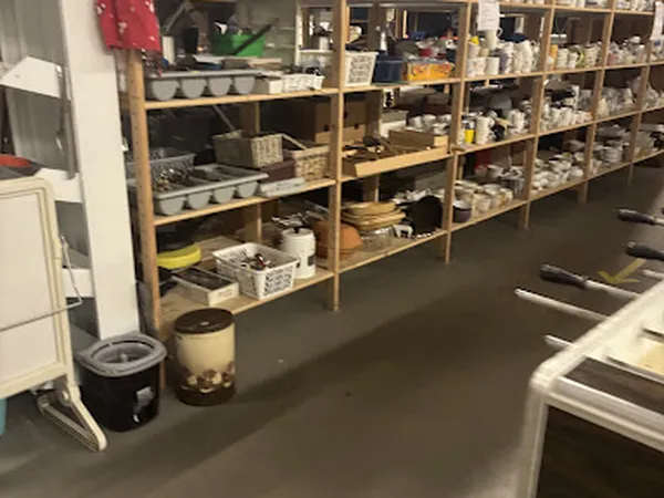 Houten stellingen met diverse spullen en huishoudartikelen in een kringloopwinkel