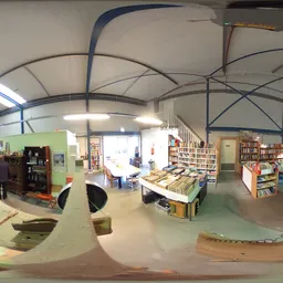 Winkelvloer met stellingen, boeken, spullen en verschillende afdelingen in een kringloopwinkel met grote raampartijen
