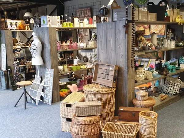Winkelvloer met rieten manden, houten rekken en diverse artikelen in een kringloopwinkel