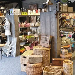 Winkelvloer met rieten manden, houten rekken en diverse artikelen in een kringloopwinkel