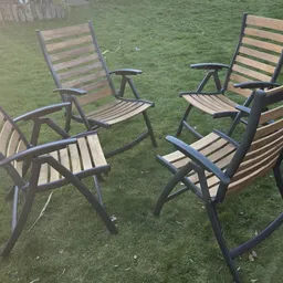 Meerdere tuinstoelen met metalen frames en houten zitting op gras
