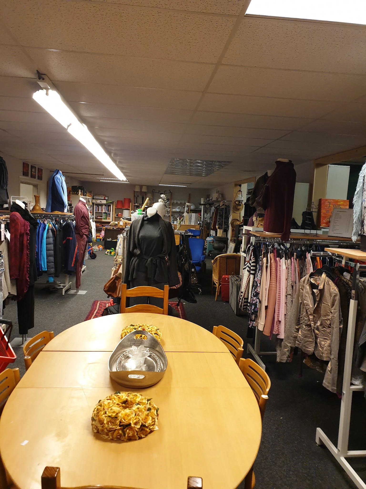 Winkelinterieur met kledingrekken, mannequins en diverse tweedehands artikelen