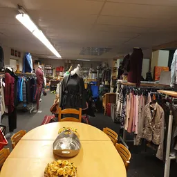 Winkelinterieur met kledingrekken, mannequins en diverse tweedehands artikelen