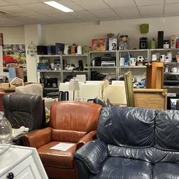 Interieur van kringloopwinkel met leren meubels en kasten vol elektronica en huishoudspullen