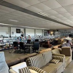 Ruim kringloopwinkelinterieur met meubels, stellingen en spullen over een groot oppervlak verspreid