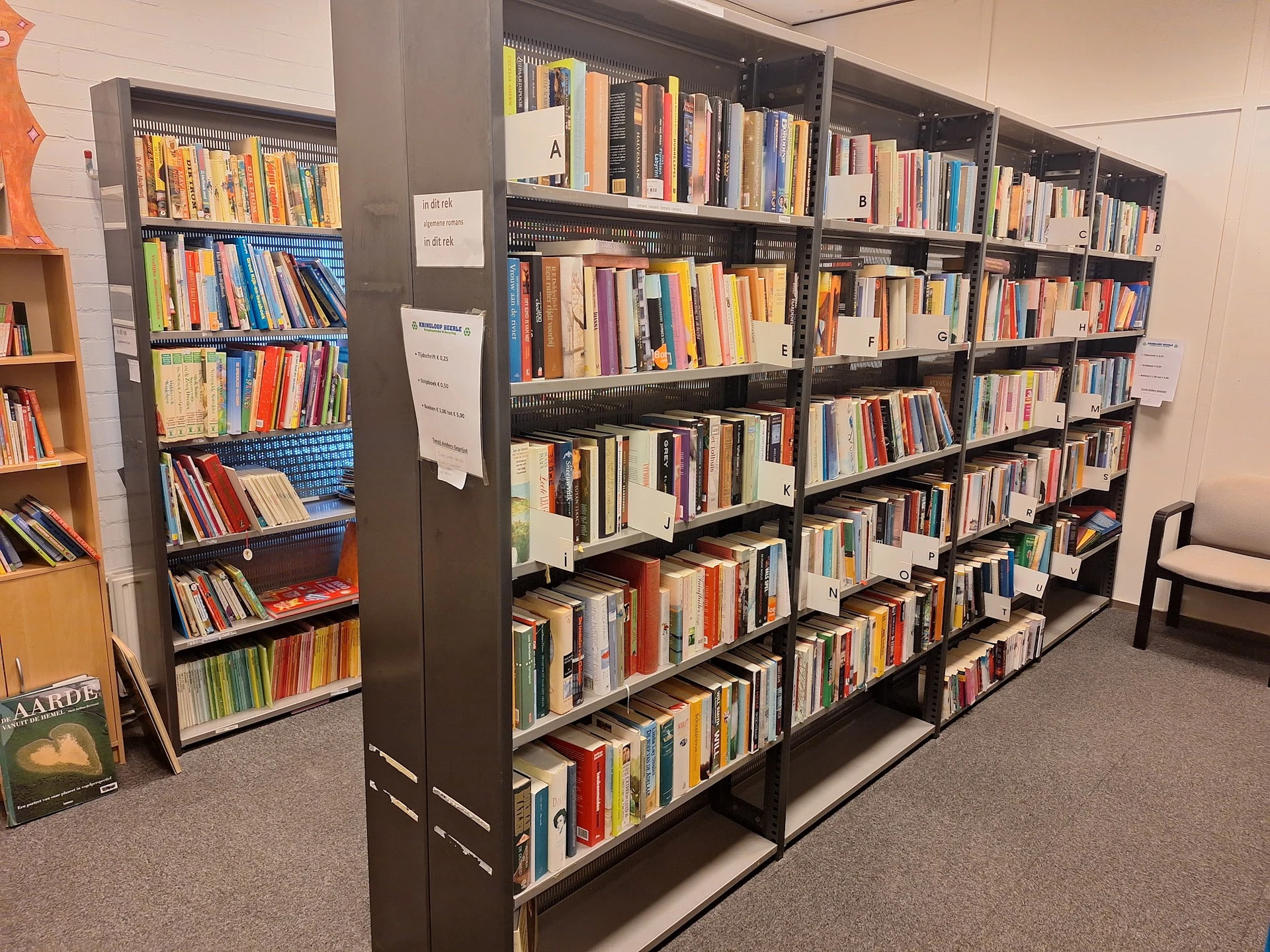 Zwarte boekenkasten gevuld met honderden tweedehands boeken, goed belicht en overzichtelijk gerangschikt