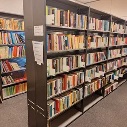 Zwarte boekenkasten gevuld met honderden tweedehands boeken, goed belicht en overzichtelijk gerangschikt