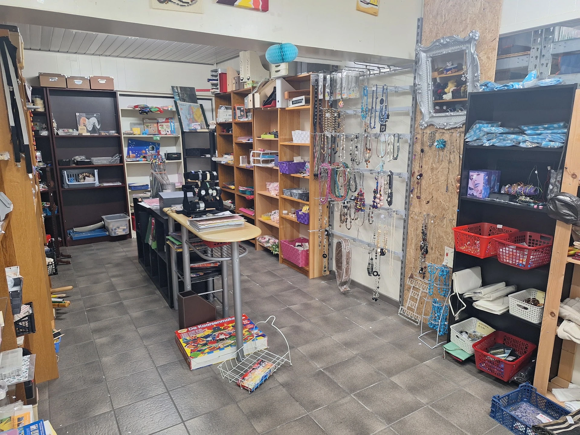 Winkelvloer van kringloopwinkel met stellingen, rekken en kasten vol spullen; diverse artikelen uitgestald op verschillende n