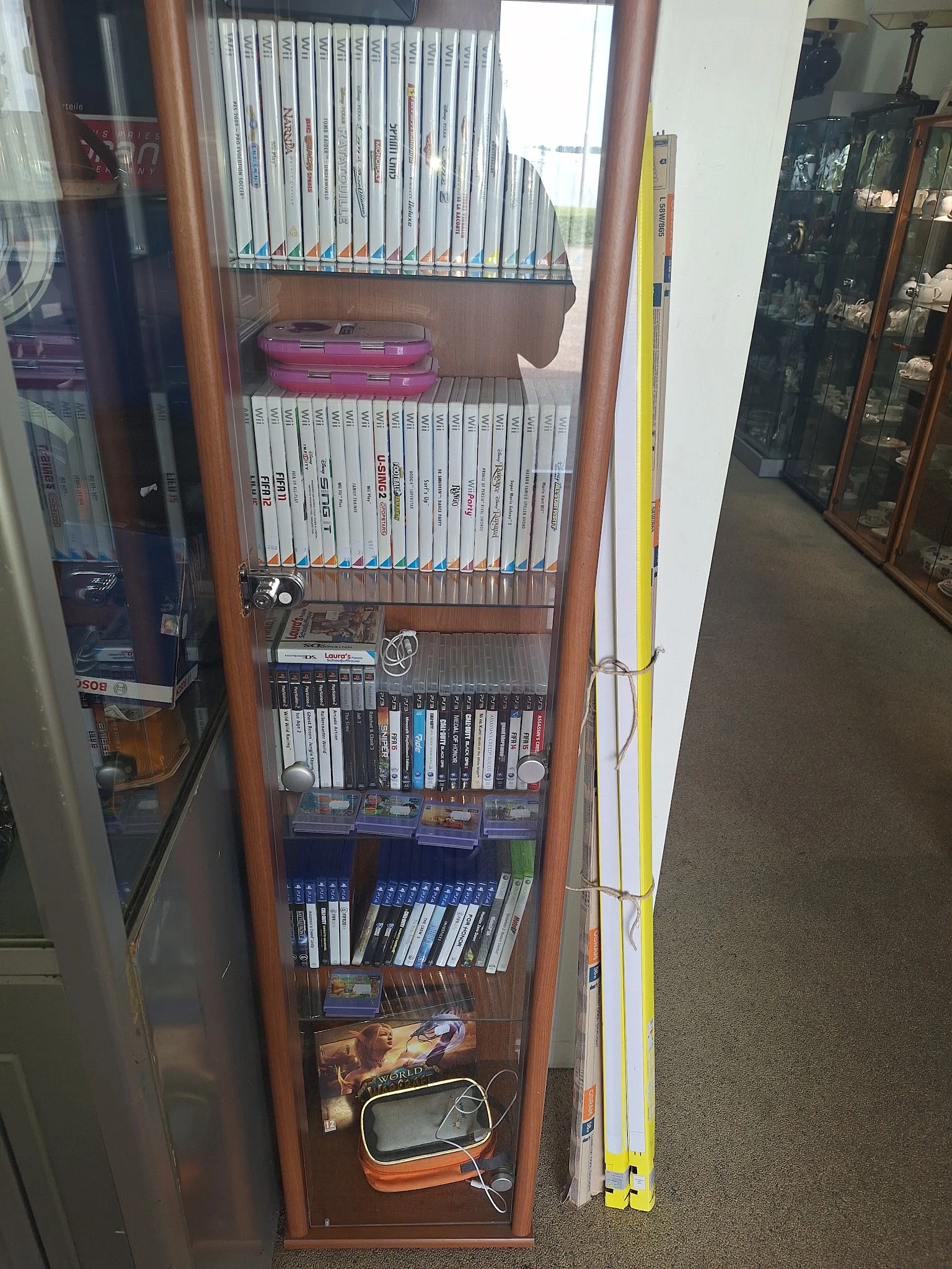 Glazen vitrinekast met uitgestalde Wii-spellen, Wii-games en gaming-accessoires op meerdere niveaus