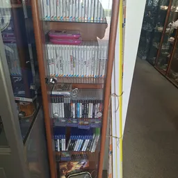 Glazen vitrinekast met uitgestalde Wii-spellen, Wii-games en gaming-accessoires op meerdere niveaus