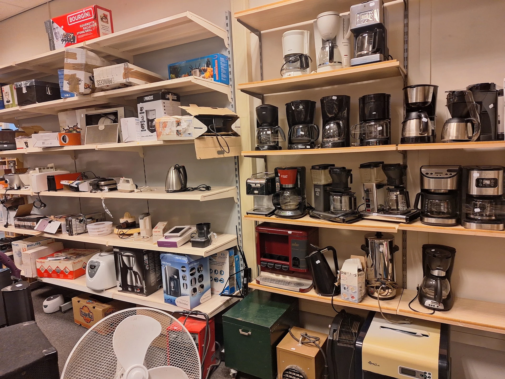 Stellingen gevuld met diverse huishoudapparaten zoals koffiezetapparaten, toasters en mixers