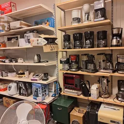 Stellingen gevuld met diverse huishoudapparaten zoals koffiezetapparaten, toasters en mixers