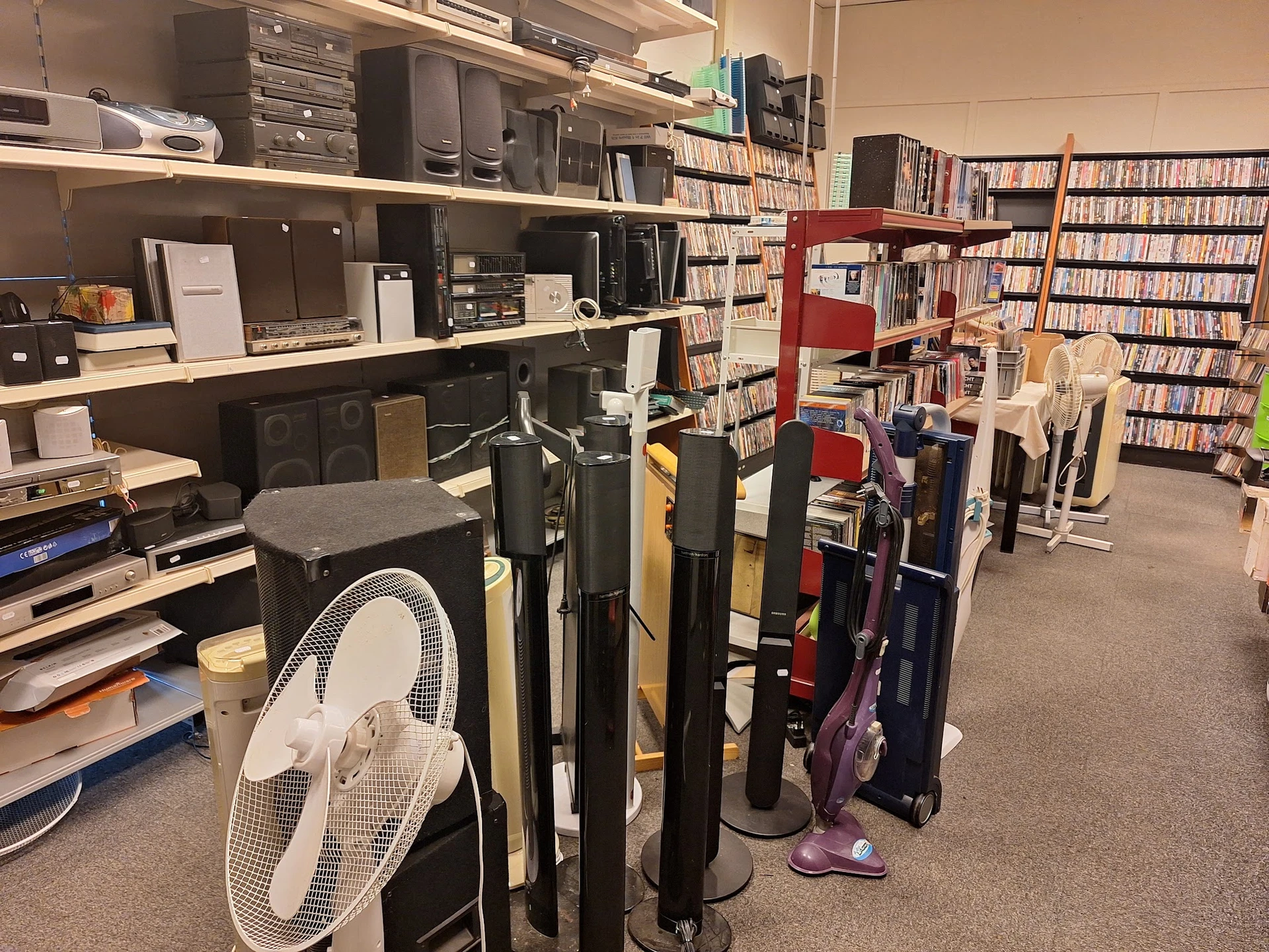 Winkelinterieur met dvd-verzameling, elektronica en diverse huishoudelijke artikelen op planken en stellingen
