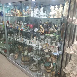 Glazen vitrinekast vol met verzamelde items zoals beeldjes, servies, decoratieve objecten en souvenirs.