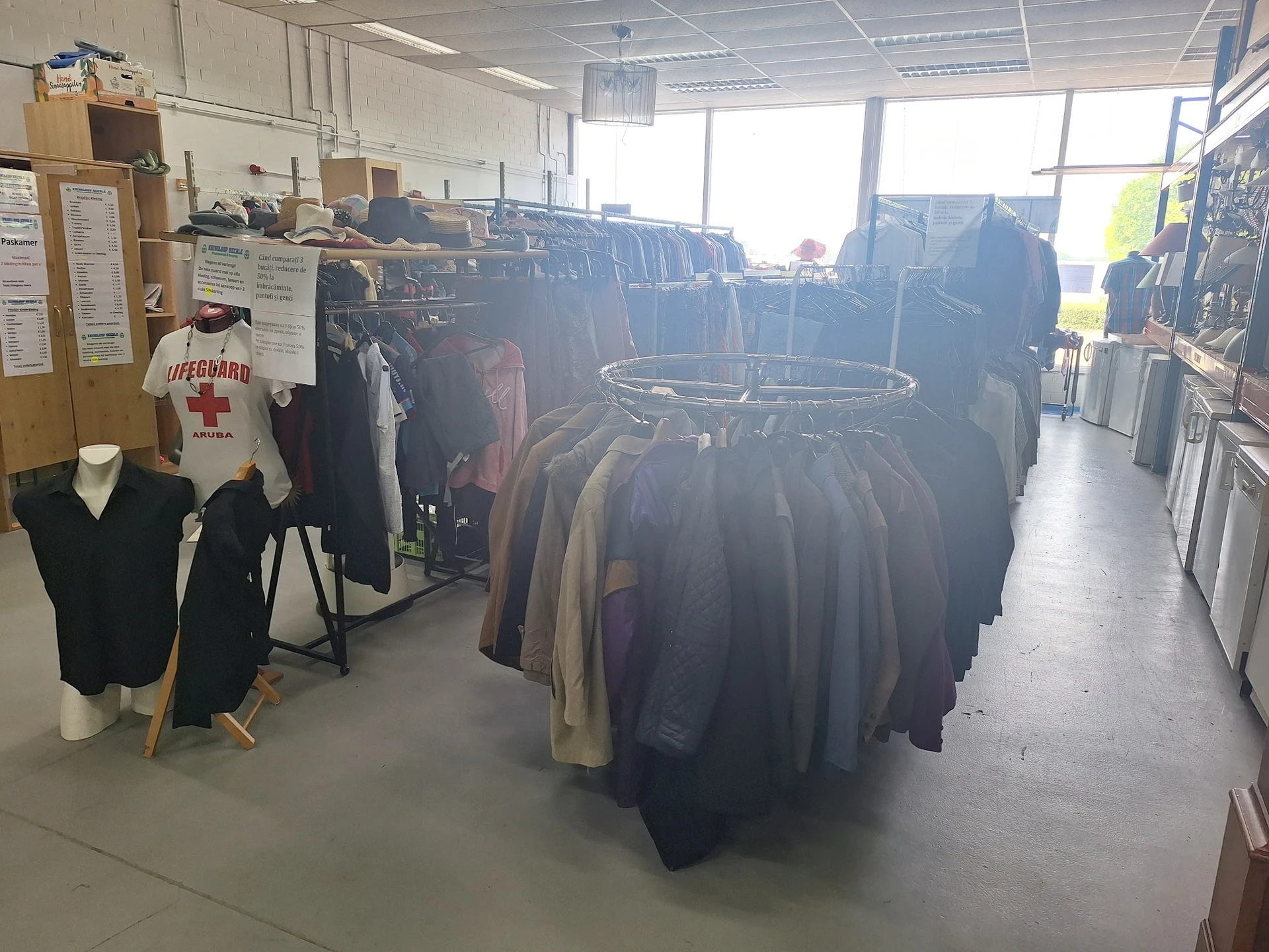 Rekken met tweedehands kleding, vooral donkere jassen en jassen in de kringloopwinkel