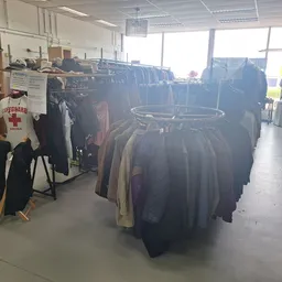 Rekken met tweedehands kleding, vooral donkere jassen en jassen in de kringloopwinkel