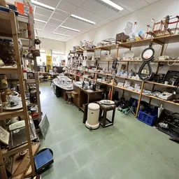 Overzicht van de winkelvloer met houten stellingen volgeladen met huishoudartikelen, servies en diversen