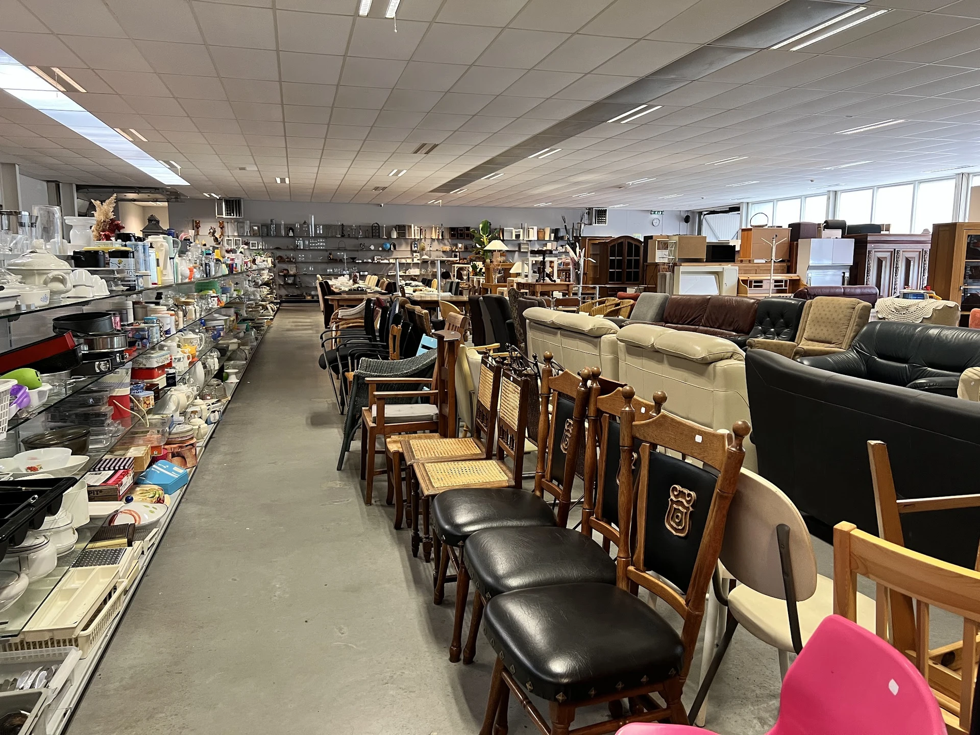 Winkelinterieur met houten stoelen, meubels en diverse artikelen op stellingen en tafels
