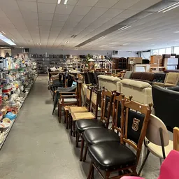 Winkelinterieur met houten stoelen, meubels en diverse artikelen op stellingen en tafels