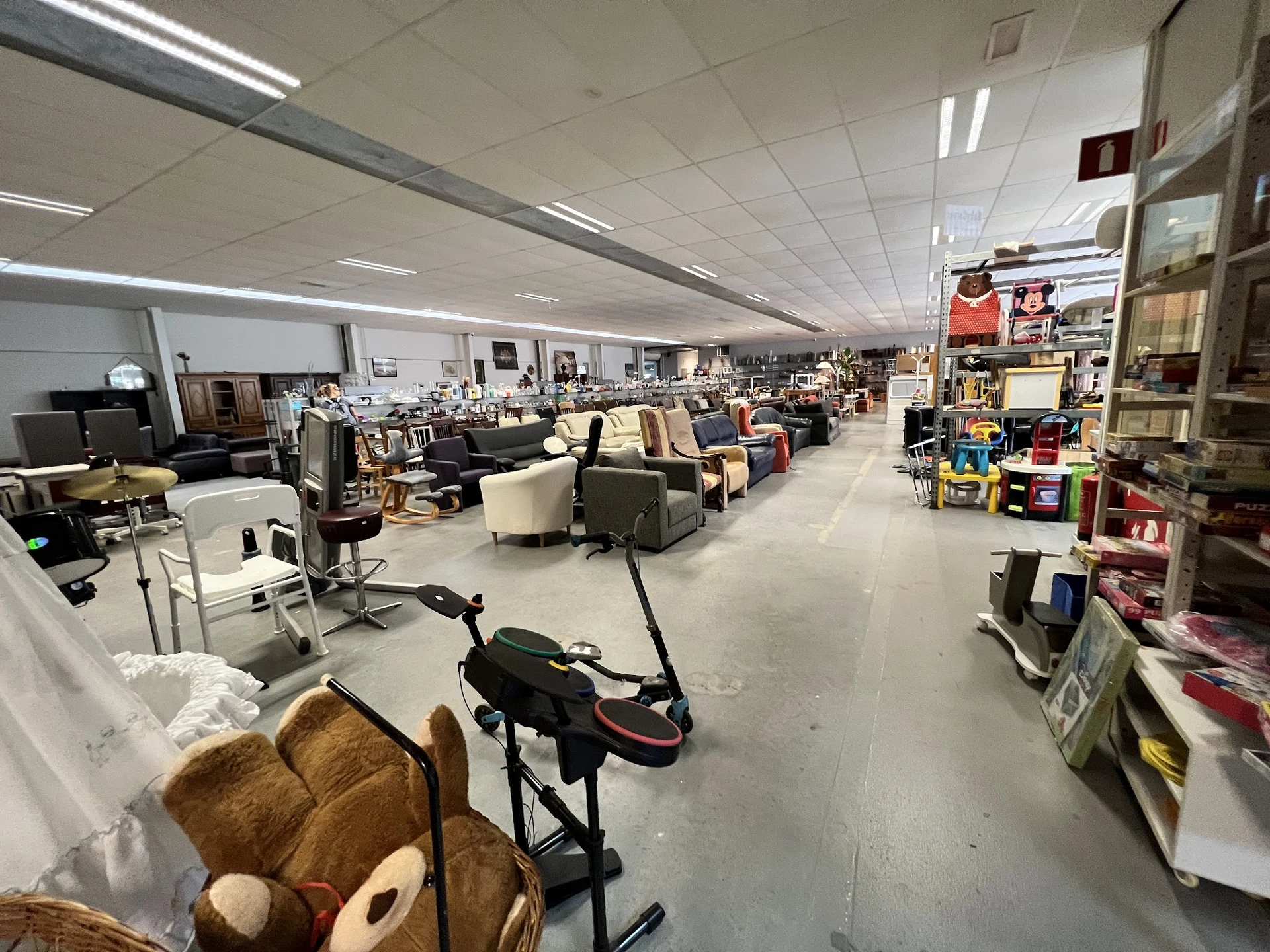 Overzicht van de winkelvloer met verschillende rekken, stoelen, tafels en diverse tweedehands spullen