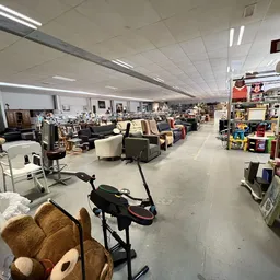Overzicht van de winkelvloer met verschillende rekken, stoelen, tafels en diverse tweedehands spullen