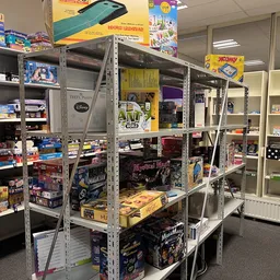Stellingen met tweedehands speelgoed, bordspellen en dvd's in een kringloopwinkel