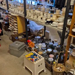 Diverse serviesgoed, potjes en huishoudelijke spullen op tafels in de winkel.