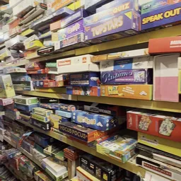 Stellingen met dozen en verpakkingen van bordspellen en spelletjes in een kringloopwinkel