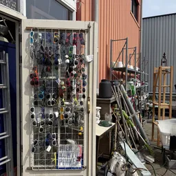 Uitgebreid assortiment zonnebrillen opgehangen aan een metalen gaas, met diverse kleuren en stijlen zichtbaar