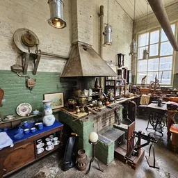 Ruim interieur van kringloopwinkel met groene muren, vintage huishoudspullen, servies en meubilair op kasten en tafels