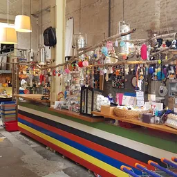 Winkelvloer van kringloopwinkel met toonbank, stellingen vol spullen en opgehangen artikelen