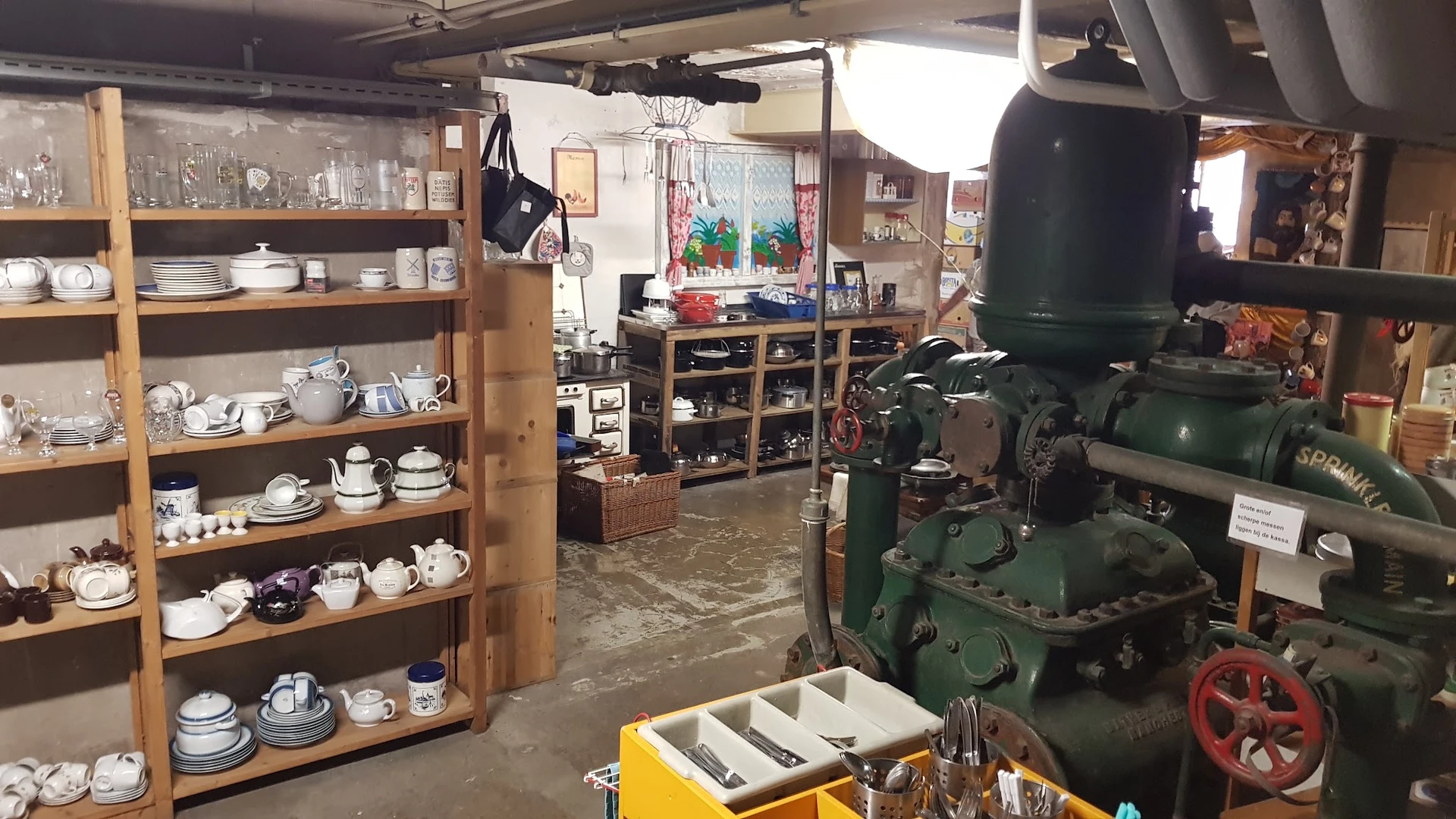Winkelbinnenruimte met houten stellingen vol servies, vintage machine en werkplek
